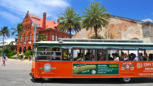 Vibrant orange Key West Hop-On, Hop-Off Trolley gracefully moving through the streets, showcasing the essence of island exploration.